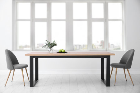 Table and chairs near big window in room. Interior design