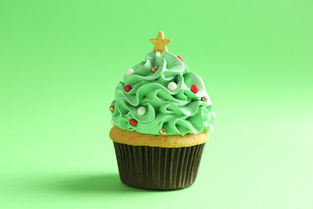 Christmas tree shaped cupcake on green background, closeupの写真素材