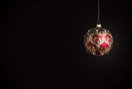 Red Christmas ball with golden pattern on black background. Festive ornamentの写真素材