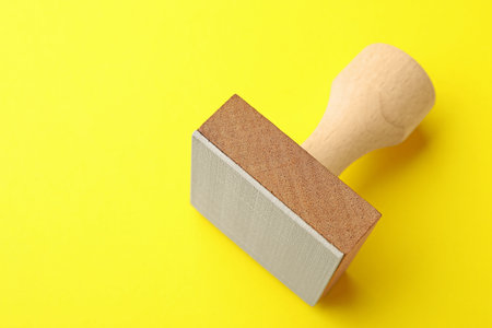One wooden stamp on yellow background, closeup. Space for textの写真素材