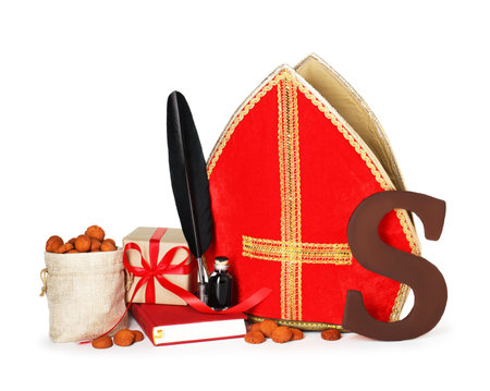 Saint Nicholas (Sinterklaas) day. Red mitre, book, feather, inkwell and traditional treats isolated on whiteの写真素材