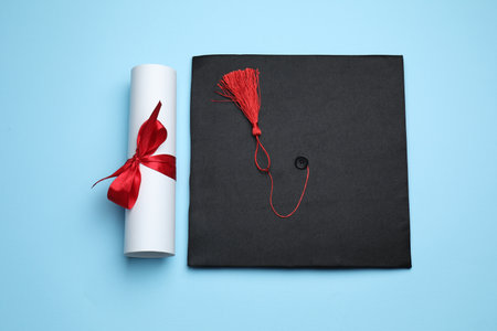 Diploma and graduation hat on light blue background, top viewの写真素材