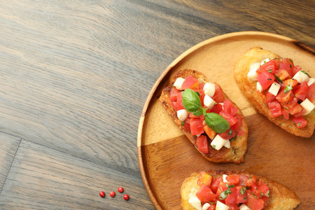 Tasty bruschettas with tomatoes, mozzarella cheese and basil served on wooden table, top view. Space for textの写真素材