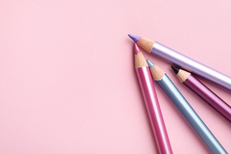 Bright eye pencils on pink background, flat lay. Space for textの写真素材