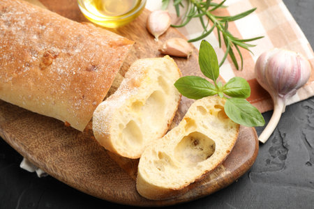 Fresh cut ciabatta, garlic and basil on dark textured table, above viewの写真素材