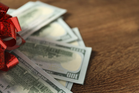 Dollar banknotes with bow on wooden background, closeup. Space for textの写真素材