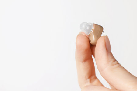 Woman with hearing aid on light background, closeup. Space for text