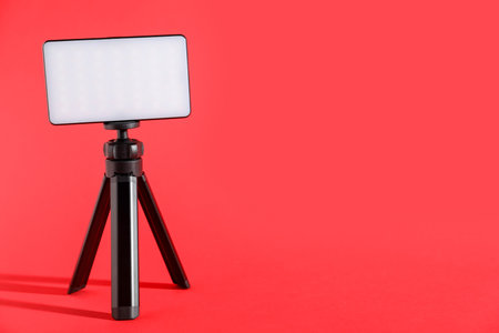 LED lamp on tripod against red background. Space for textの写真素材