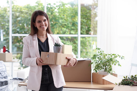 Moving day. Woman holding box with different belongings in officeの写真素材