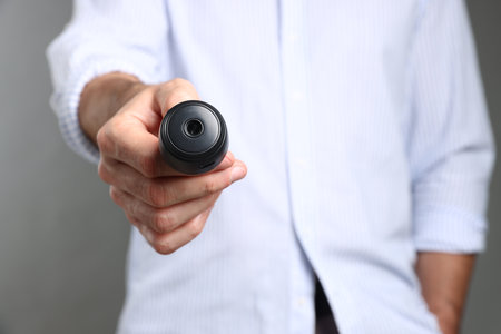 Man with hidden spy camera on gray background, closeupの写真素材