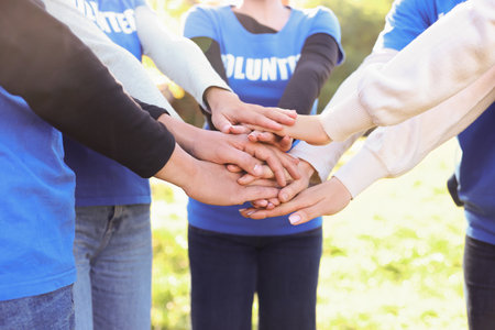 Group of volunteers stacking hands outdoors, closeupの写真素材