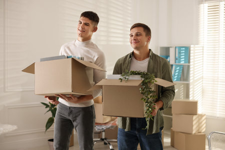 Moving day. Workers holding cardboard boxes with different belongings in office