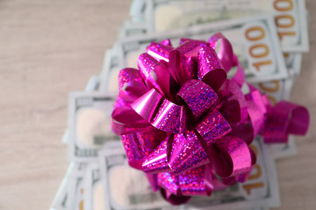 Dollar banknotes with bow on light wooden background, flat layの写真素材