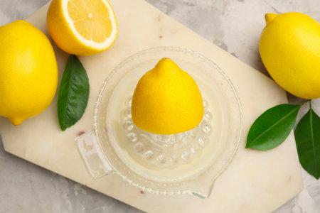 Lemon juice in juicer, leaves and fresh lemons on light gray table, flat layの写真素材