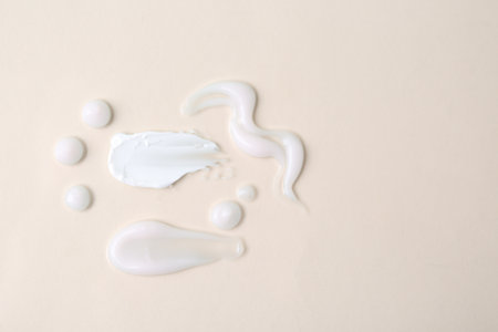 Samples of moisturizing creams on beige background, flat lay. Space for textの写真素材
