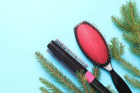 Hairdresser's tools and fir tree branches on light blue background, flat lay with space for text. Christmas greeting cardの写真素材