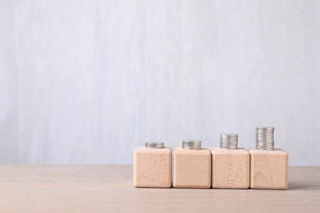 Blank cubes and stacked coins on wooden table. Mockup for designの写真素材