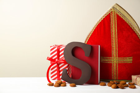 Sinterklaas (Saint Nicholas) Day. Chocolate letter S, kruidnoten cookies. Gifts and notebook on white table. Space for textの写真素材