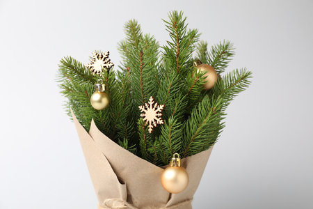 Beautiful Christmas tree branches with festive decor wrapped in paper on gray background, closeupの写真素材