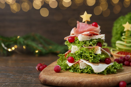 Christmas tree shaped snack made with lettuce, ham, croutons and berries on wooden table, closeupの写真素材