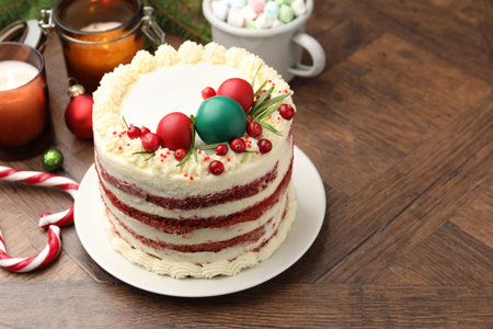 Delicious sponge cake with Christmas decor and red currants on wooden table, closeup. Space for text
