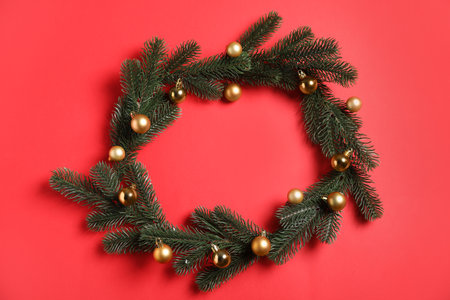 Frame made of Christmas tree branches with baubles on red background, flat lay. Space for textの写真素材