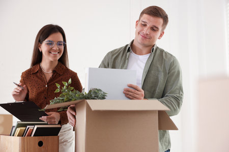 Moving day. Workers putting different belongings into cardboard boxes in office