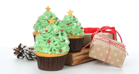 Christmas tree shaped cupcakes, pine cones and gift boxes isolated on whiteの写真素材