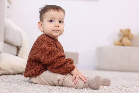 Cute little baby sitting on floor at homeの写真素材