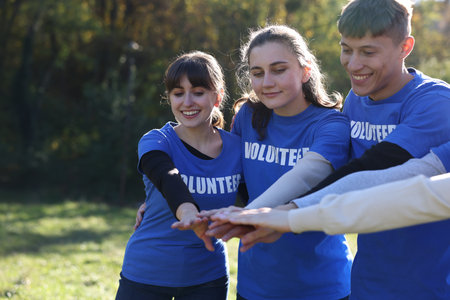 Group of happy volunteers stacking hands in parkの写真素材