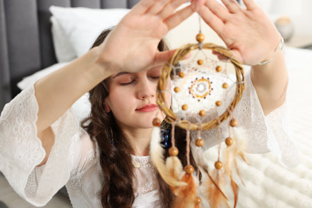 Woman with beautiful dream catcher in bedroomの写真素材