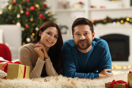 Happy couple spending time together in room decorated for Christmasの写真素材