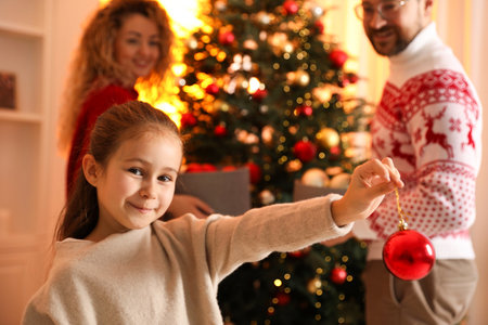 Little girl with bauble and her parents decorating Christmas tree at home, selective focusの写真素材