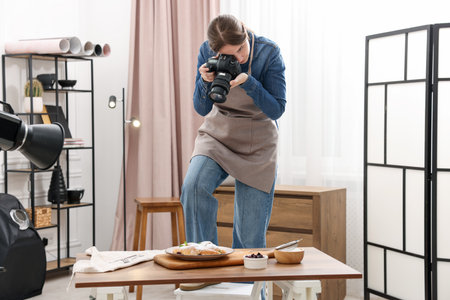 Woman taking picture of croissants at table in studio. Professional food photographyの写真素材