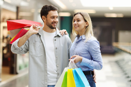 Happy couple with different shopping bags in mallの写真素材