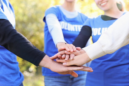 Group of volunteers stacking hands outdoors, closeupの写真素材