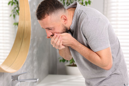 Man suffering from stomach ache and nausea in bathroom