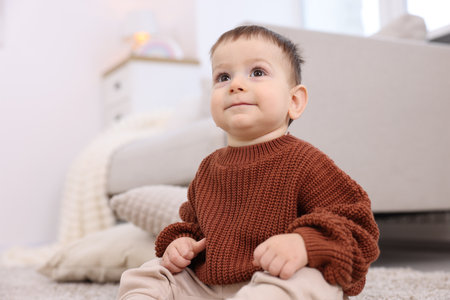 Cute little baby sitting on floor at homeの写真素材
