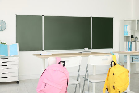 Green chalkboard and stylish furniture in classroom. Mockup for design