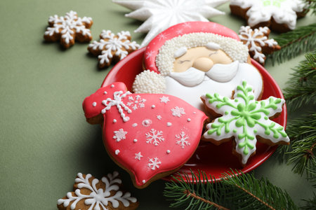 Christmas treat. Tasty gingerbread cookies and fir tree branches on green background, closeup. Space for textの写真素材