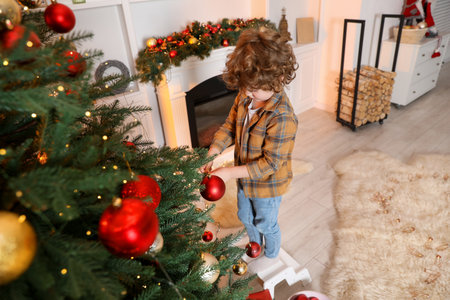 Little boy decorating Christmas tree at home, above viewの写真素材