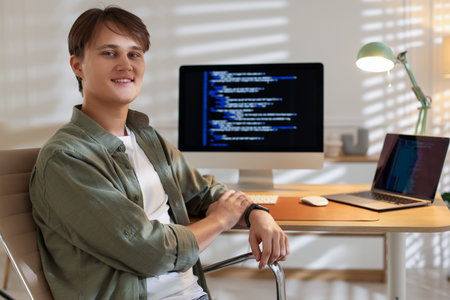 Portrait of smiling programmer on chair at workplaceの写真素材