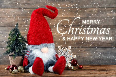 Merry Christmas and Happy New Year greeting card. Cute gnome and other festive decor on wooden tableの写真素材