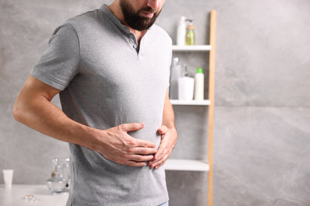 Man suffering from stomach ache and nausea in the bathroom, closeup.