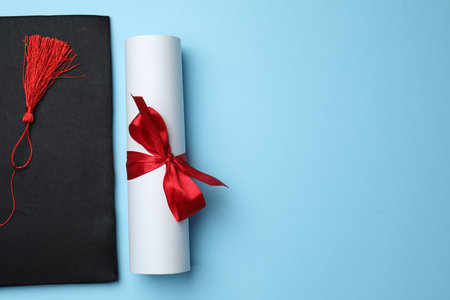 Diploma and graduation hat on light blue background, top view. Space for textの写真素材