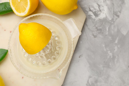 Lemon juice in juicer, leaves and fresh lemons on light gray table, flat lay. Space for textの写真素材