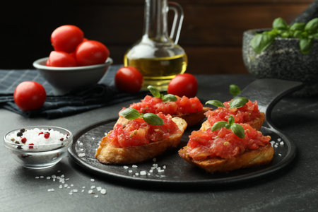 Tasty bruschettas with tomatoes and basil served on black table, closeupの写真素材