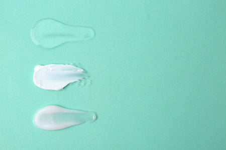 Samples of cosmetic products on turquoise background, flat lay. Space for text