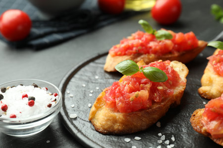 Tasty bruschettas with tomatoes and basil served on black table, closeupの写真素材