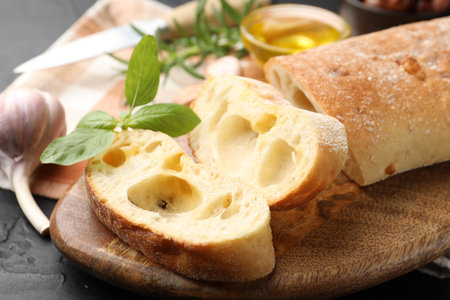 Fresh cut ciabatta, garlic and basil on dark textured table, closeupの写真素材
